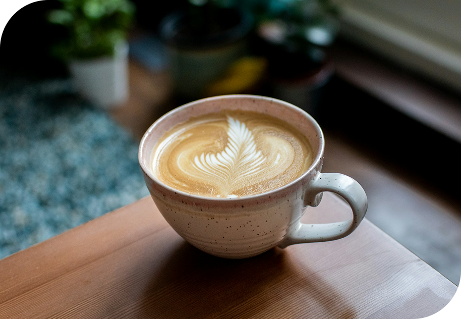 Café latte sur table en bois dans une ambiance chaleureuse, illustrant la page Contact de NUA Webdesign – contact webdesigner NUA Webdesign