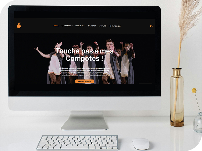 Mockup du site « Touche pas à mes Compotes » affiché sur un iMac, présentant la page d’accueil du site de la compagnie artistique avec son visuel de spectacle et le bouton de réservation.